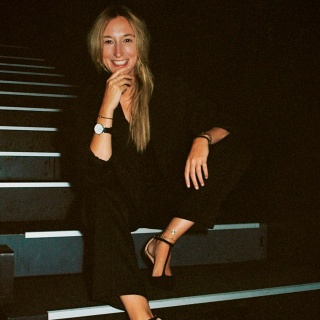 Marieke Reimann sitzt auf der Treppe in einem schwarzen Hosenanzug