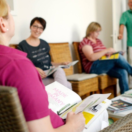 Ein Arzt ruft den nächsten Patienten im Wartezimmer auf