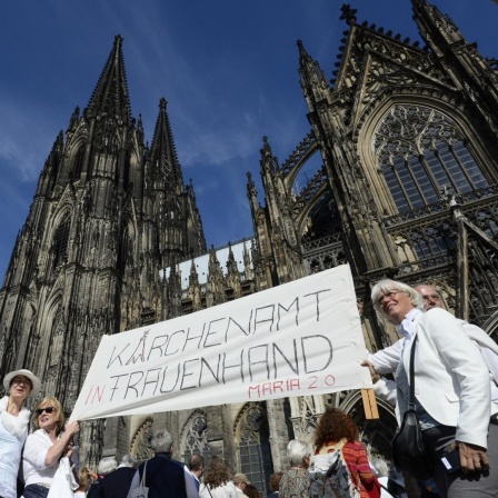 Demonstrantinnen der Bewegung Maria 2.0 stehen mit einem Transparent mit der Aufschrift "Kirchenamt in Frauenhand - Maria 2.0" vor dem Kölner Dom.