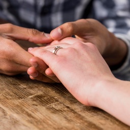 Junger Mann hält Hand mit Ring seiner Freundin