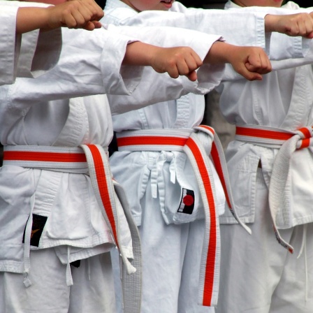 Kinder in Judoanzügen stehen nebeneinander und strecken die Fäuste aus