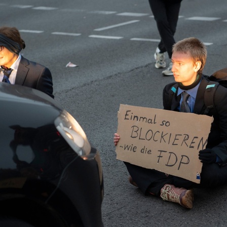 Aktivisten der Gruppe &#034;Letzte Generation&#034; sitzen auf einer Kreuzung an der Landsberger Allee. Aufgrund der Blockade kam es zu erheblichen Verkehrsbehinderungen.