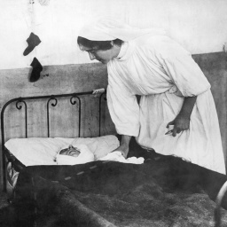 Historisches schwarz-weiß Foto. Frankreich am 21. November 1914. Eine Krankenschwester kümmert sich um einen schwer verwundeten Soldaten, der in einem Krankenbett liegt.