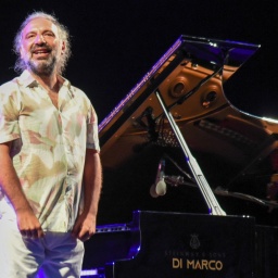Jazzpianist Stefano Bollani steht während eines Konzerts neben dem Flügel und schaut ins Publikum.