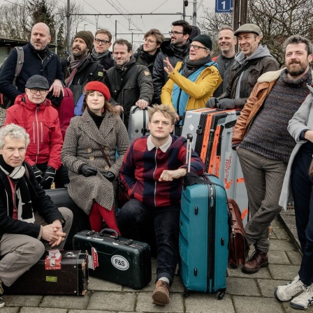 Die Band "Flat Earth Society" auf einem Bahnsteig.