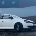 Ein Auto der Marke VW mit der US-Fahne im Hintergrund.