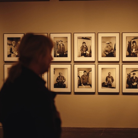 Eine Besucherin vor mehreren Fotos in der Ausstellung "Christina Glanz. Fotografien einer Transformation"