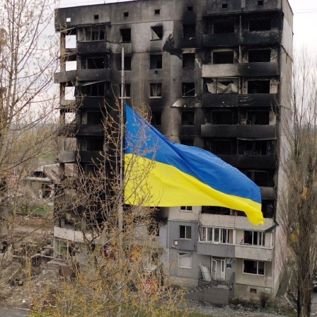 Eine ukrainische Fahne weht vor von russischen Raketen zerstörten Gebäuden in Kiew.