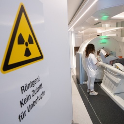 Medizinisch-technische Radiologieassistentin, spricht mit einem Mann in einem mobilen Computertomographen CT, bevor er sich einem Lungencheck unterzieht.