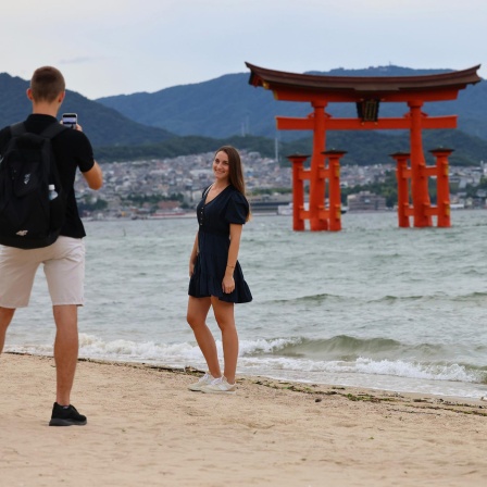 Junge Menschen machen Handy-Fotos vor dem Itsukushima-Schrein, ein Unesco-Weltkulturerbe in Japan.