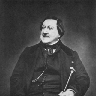 Ein Mann in Anzug sitzt und blickt nach recht. Es ist der Komponist Gioachino Rossini. Es ist eine Schwarz-Weiß-Aufnahme.