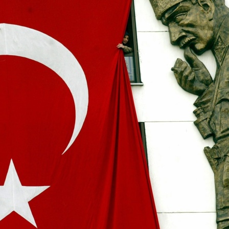 Neben einer riesigen Flagge der Türkei an einer Hauswand sieht man die Plastik des Staatsgründers Kemal Atatürk.