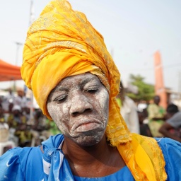 Frau mit Kopftuch und weiß geschminktem Gesicht beim jährlichen Voodoo-Festival in Benin