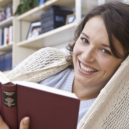Ein Frau liest in der Hängematte: Lesen soll den Blutdruck senken, das Gehirn fit halten und sogar unser Leben verlängern. Was ist dran an diesen Thesen?