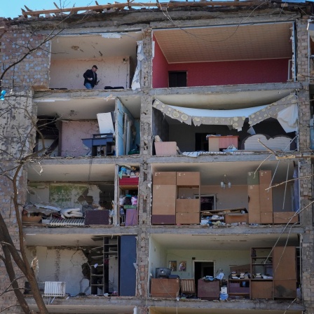 Ein Mann steht in seiner Wohnung die nach einem russischen Angriff zerstört ist.