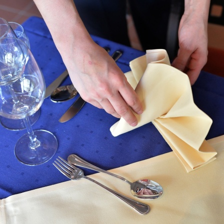 Eine Hotelfachangestellte stellt 2013 eine Serviette auf einen Tisch.