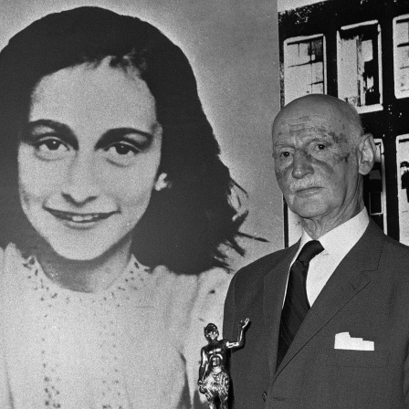 Otto Frank steht vor einem Bild seiner Tochter Anne Frank.