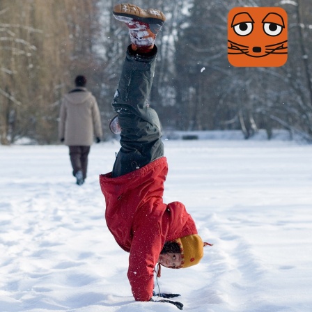 Kind macht einen Handstand im Schnee