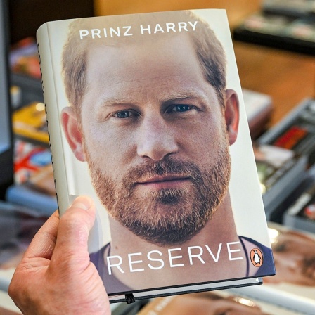 Jemand hält Prinz Harrys Autobiografie "Spare" in der Hand.