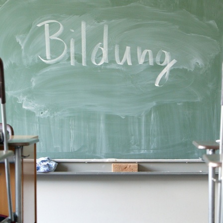 Eine Tafel in einem Klassenraum, auf der mit Kreide das Wort "Bildung" geschrieben wurde. Symbolbild