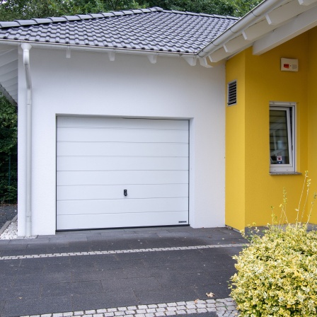 Ein Garagentor neben einer gelben Hauswand.