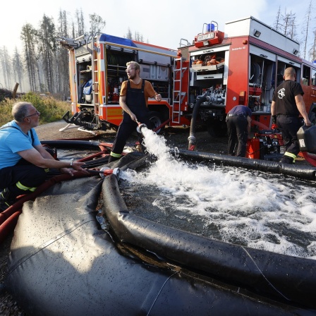 Rettungskräfte der Feuerwehr füllen einen Zusammenklappbaren Wassertank mit Wasser als sie einen größeren Waldbrand in Schierke bekämpfen
