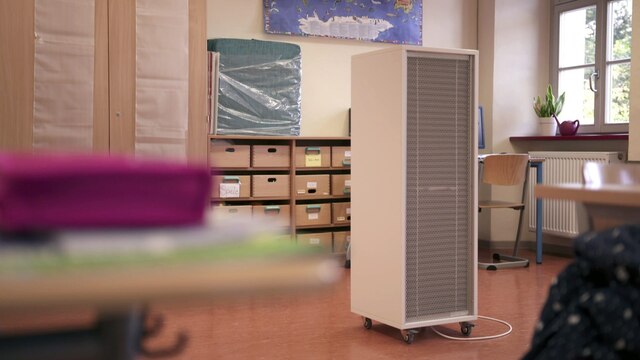 Ein kastgenförmiger Luftfilter steht in einem Klassenraum.