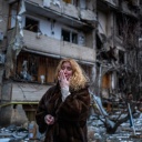 Eine Frau weint neben einem zerstörten Wohnhaus