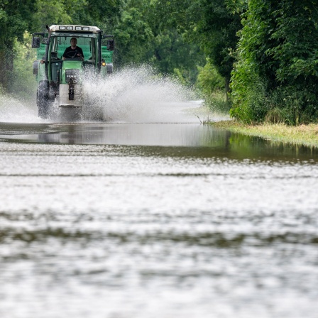 Ein Traktor fährt in Baar-Ebenhausen durch eine überflutete Straße. Extremer Dauerregen in Bayern, In wehreren drei Landkreisen gilt der Katastrophenfall.