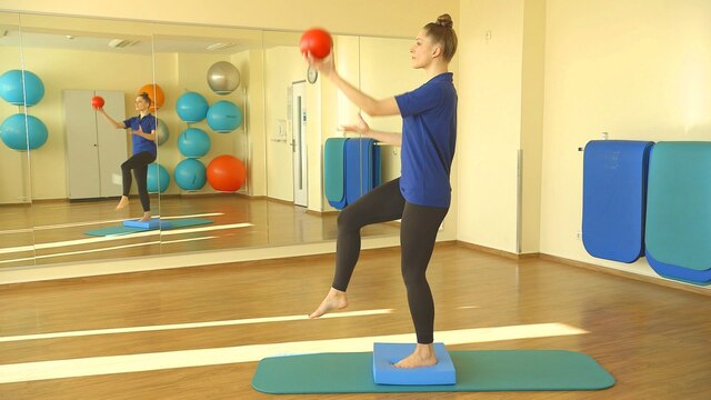 Physiotherapeutin Svea Köhlmoos hält auf einem Bein stehend einen Ball hoch.