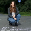 Lisanne Richter vor einem mit Kreide geschriebenen Text auf einer Straße.