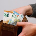 Eine Frau zählt ihre Geldscheine ihrem Portemonnaie.