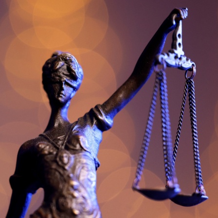 Eine Bronzestatue der Justitia steht auf einem Tisch.