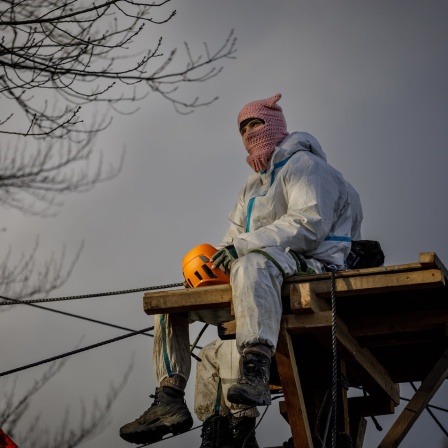 Aktivist sitzt auf Hochsitz, dämmriger Himmel