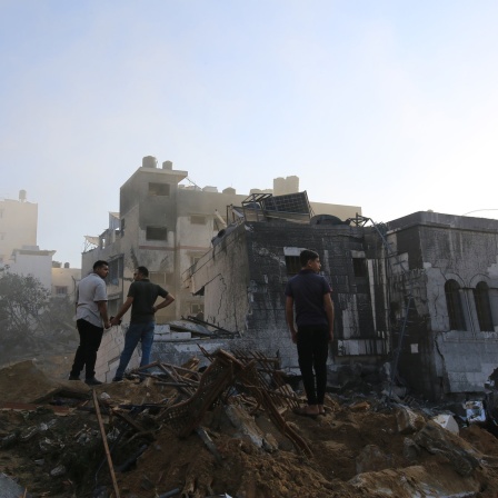 Menschen stehen nach einem israelischen Raketenangriff auf den Trümmern in Gaza-Stadt