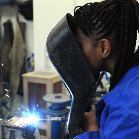 Junge Frau aus dem Guinea schweißt in einer Metallwerkstatt, Symbolbild