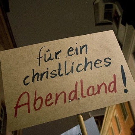 Bei einer Demonstration in Villingen-Schwenningen halten Pegida-Anhänger ein Schild in die Höhe, darauf steht "für ein christliches Abendland"; das Foto zeigt das Plakat und im Hintergrund Häuser (26.01.2015); Foto:dpa