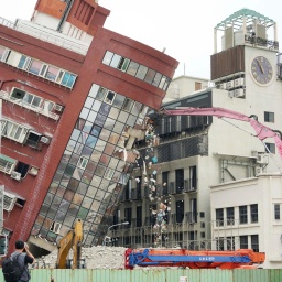 Ein Haus ist nach einem Erdbeben in Taiwan zur Seite gestürzt und wird von einem Bagger abgetragen.