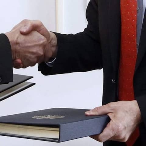 Botschafter und Finanzminister reichen sich die Hand (Symbolbild)