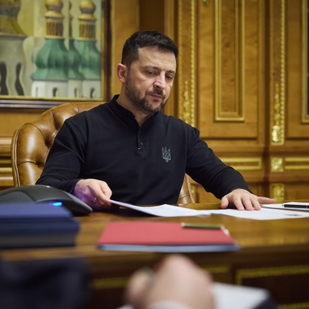 Selenskyj mit Dokumenten an einen Schreibtisch