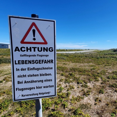 Ein Warnschild weist auf die Einflugschneise des kleinen Flughafens von der Insel Helgoland hin.