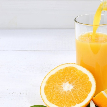 Orangensaft wird in ein Glas gegossen