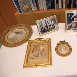 Blick auf vier als NS-Raubkunst identifizierte Zeichnungen, die heute an die Erben der ursprünglichen Eigentümerin zurückgegeben wurden, und daneben Fotos und das Wohnhaus der ehemaligen Eigentümerin. 