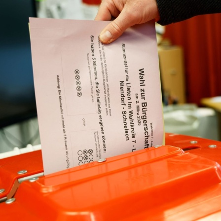 Eine Wählerin steckt ihren Stimmzettel in eine Wahlurne im Wahllokal in der Julius-Leber-Schule in Hamburg-Schnelsen. In Hamburg wird am Sonntag eine neue Bürgerschaft gewählt.