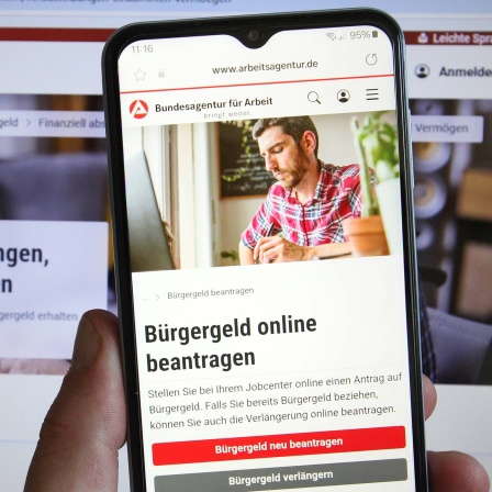 Bildschirm und Smartphone-Display mit Informationen des Jobcenters zum Bürgergeld.